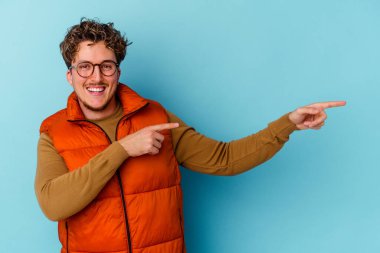 Mavi arka planda gözlük takan genç beyaz adam işaret parmağıyla işaret ederek heyecanlanıyor..