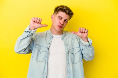 Sarı arka planda izole edilmiş genç beyaz adam gururlu ve kendinden emin hissediyor, örnek olarak.