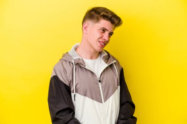 Sarı arka planda izole edilmiş genç beyaz adam gülümseyen, neşeli ve keyifli görünüyor..