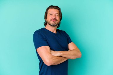 Mavi arka planda tek başına duran orta yaşlı bir adam