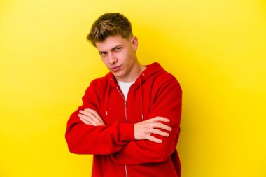 Genç beyaz adam sarı arka planda izole edilmiş şüpheli, belirsiz, seni muayene ediyor..