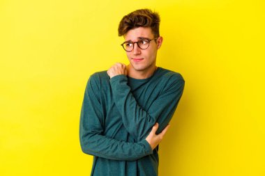 Sarı arka planda izole edilmiş genç beyaz adam şaşkın, şüpheli ve güvensiz hissediyor..
