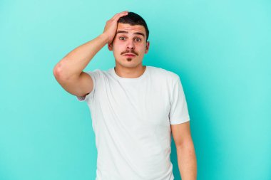 Mavi arka planda izole genç beyaz adam şok oldu, o önemli bir toplantı hatırladı.