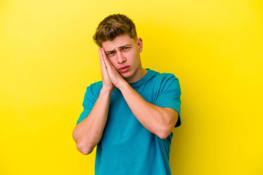 Sarı arka planda izole edilmiş genç beyaz adam esniyor. Ağzı eliyle kapatan yorgun bir hareket sergiliyor..