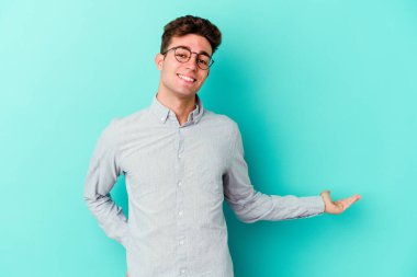 Mavi arka planda izole edilmiş beyaz bir genç hoş bir yüz ifadesi sergiliyor..