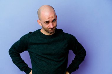 Mor arka planda izole edilmiş beyaz kel bir adam yanakları patlatır, yorgun bir ifadeye sahiptir. Yüz ifadesi kavramı.