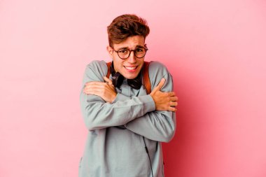 Pembe arka planda izole olmuş genç bir öğrenci düşük sıcaklıktan ya da hastalıktan soğuyor..
