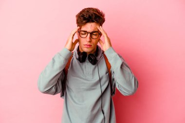 Pembe arka planda izole edilmiş genç bir öğrenci tapınaklara dokunuyor ve başı ağrıyor..