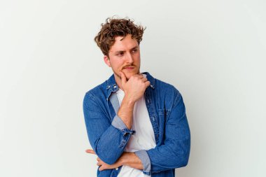 Beyaz arka planda soyutlanmış genç beyaz bir adam düşünüyor ve yukarı bakıyor, yansıtıyor, düşünüyor, hayal kuruyor..