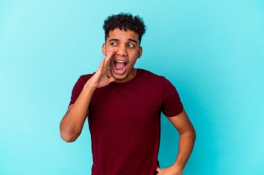 Genç Afro-Amerikalı kıvırcık adam, mavi üzerine izole edilmiş, heyecanlı bir şekilde bağırıyor..