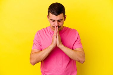 Sarı arka planda izole edilmiş genç, beyaz bir adam. Dua ediyor, bağlılık gösteriyor. İlahi ilhamı arayan dindar biri..