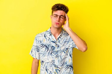 Sarı arka planda izole edilmiş genç beyaz adam yorgun ve uykulu bir şekilde ellerini başının üstünde tutuyor..