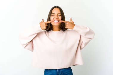 Genç melez kadın gülümsüyor, parmaklarıyla ağzını işaret ediyor..