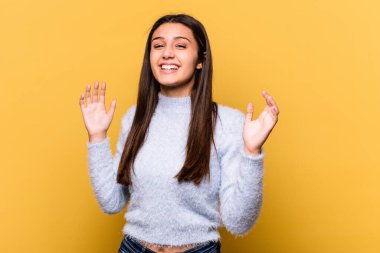 Sarı arka planda izole edilmiş genç Hintli kadın neşeli bir şekilde gülüyor. Mutluluk kavramı.