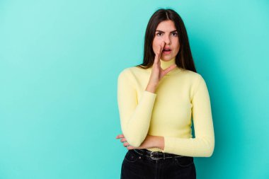 Mavi arka planda izole edilmiş genç beyaz kadın gizli bir sıcak fren haberi veriyor ve yana bakıyor.