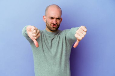 Mor arka planda soyutlanmış beyaz kel bir adam baş parmağını aşağı gösteriyor ve hoşlanmadığını ifade ediyor..