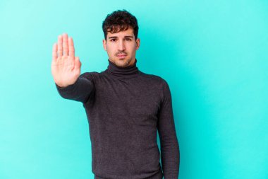 Mavi arka planda izole edilmiş genç beyaz adam elini uzatmış, dur işareti göstererek seni engelliyor..