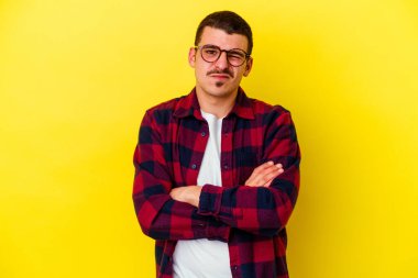 Sarı arka planda izole edilmiş genç beyaz adam alaycı bir ifadeyle kameraya bakıyor..