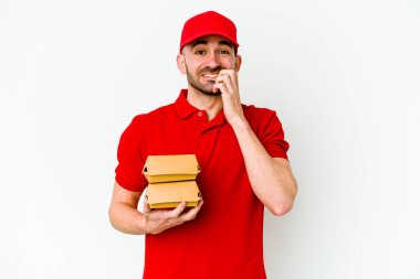 Beyaz arka planda izole edilmiş, tırnak yiyen, gergin ve endişeli genç beyaz bir teslimatçı..