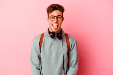 Pembe arka planda izole edilmiş genç bir öğrenci komik ve dost canlısı bir dil uzatıyor..