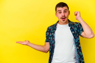 Sarı arka planda izole edilmiş beyaz bir genç, bir avuç içinde fotokopi alanı tutuyor, el üstünde tutuyor. Şaşırmış ve mutlu..