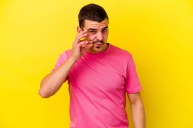 Sarı arka planda izole edilmiş, dudakları dudaklarında bir sır saklayan genç beyaz bir adam..