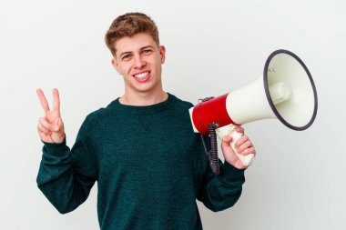 Beyaz arka planda izole edilmiş bir megafon tutan genç beyaz bir adam neşeli ve kaygısız parmakları olan bir barış sembolü gösteriyor..