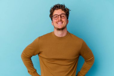 Gözlüklü genç beyaz adam mavi arka planda izole edildi..