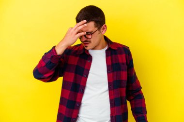 Sarı arka planda izole edilmiş, başı ağrıyan, yüzünün ön kısmına dokunan genç beyaz bir adam..