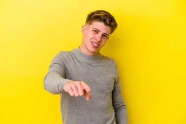 Sarı arka planda izole edilmiş genç beyaz adam öne bakan neşeli gülücükler.