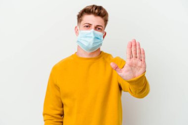 Koronavirüs maskesi takan genç bir adam beyaz arka planda izole edilmiş, elini uzatmış, dur işaretini göstererek seni engelliyor..
