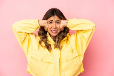 Kafkasyalı genç bir kadın, kulaklarını elleriyle kapatıyor ve yüksek sesli sesler duymamaya çalışıyor..