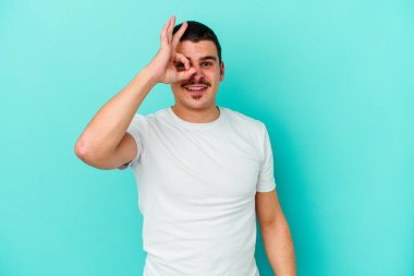 Kafkasyalı genç adam mavi arka planda izole edildi. Heyecanlı görünüyor..