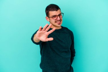 Mavi arka planda izole edilmiş genç beyaz adam tiksinti belirtisi gösteren birini reddediyor..