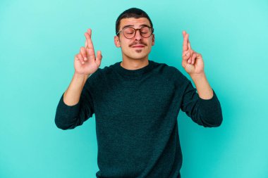Kafkasyalı genç adam mavi arka planda izole edilmiş şans dilemek için şans diliyor.