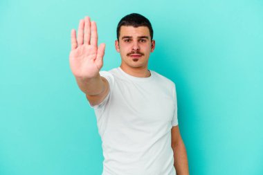 Mavi arka planda izole edilmiş genç beyaz adam elini uzatmış, dur işareti göstererek seni engelliyor..