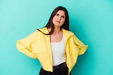 Mavi arka planda izole edilmiş genç beyaz kadın yanakları patlatıyor, yorgun bir ifadesi var. Yüz ifadesi kavramı.