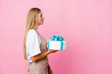 Genç Rus fırıncı kadın elinde lezzetli bir pasta, sola bakıyor, yandan bakıyor..