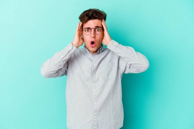 Mavi arka planda izole genç beyaz adam şok oldu, o önemli bir toplantı hatırladı.