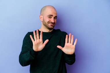 Mor arka planda izole edilmiş beyaz kel bir adam iğrenme hareketi gösteren birini reddediyor..