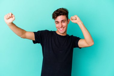 Genç beyaz adam mavi arka planda izole edilmiş dans ediyor ve eğleniyor..