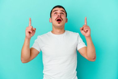 Mavi arka planda izole edilmiş beyaz bir adam ağzı açık bir şekilde üst tarafı işaret ediyor..