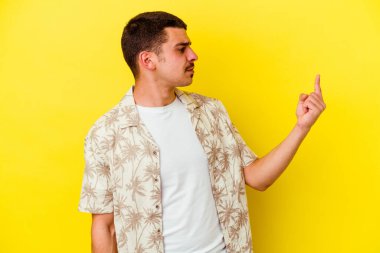 Sarı arka planda izole edilmiş genç beyaz adam sanki seni davet ediyormuş gibi seni işaret ediyor..
