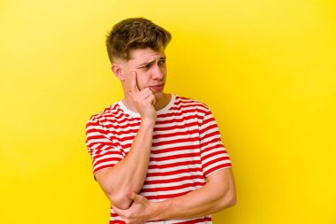 Kafkasyalı genç bir adam sarı arka planda izole edilmiş. Bir strateji planlıyor, bir iş yolu düşünüyor..