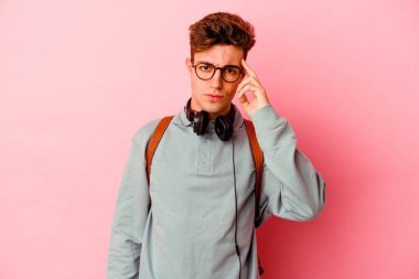Pembe arka planda izole edilmiş genç bir öğrenci parmağıyla tapınağı işaret ediyor, düşünüyor ve bir göreve odaklanıyor..