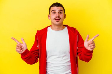 Sarı arka planda izole edilmiş genç beyaz adam farklı kopya alanlarını gösteriyor, birini seçiyor, parmaklarıyla gösteriyor..