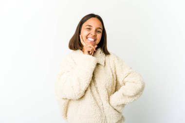 Genç melez kadın gülümsüyor mutlu ve kendinden emin, elleriyle çenesine dokunuyor..