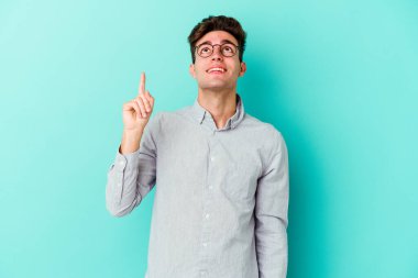 Mavi arka planda izole genç beyaz adam işaret iki ön parmakları boş bir boşluk gösteren.