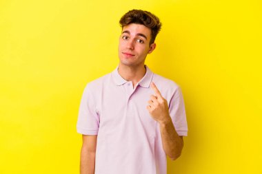 Sarı arka planda izole edilmiş genç beyaz adam sanki seni davet ediyormuş gibi seni işaret ediyor..