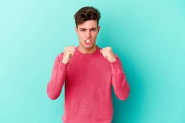 Mavi arka planda izole edilmiş genç beyaz adam gergin elleriyle çığlık atıyor..